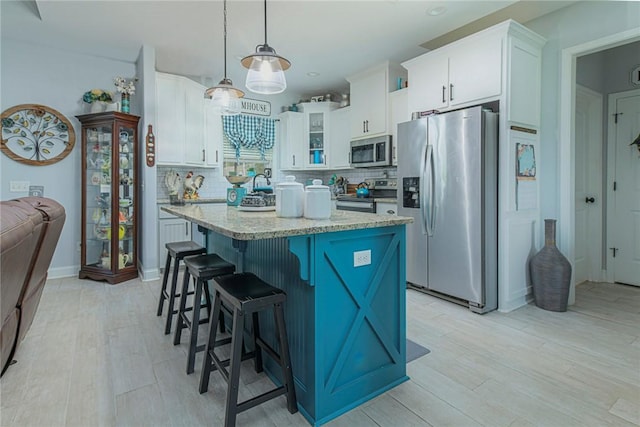 kitchen featuring appliances with stainless steel finishes, a center island, white cabinetry, and decorative backsplash