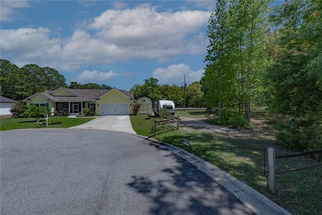 ranch-style home featuring an attached garage, fence, concrete driveway, and a front yard