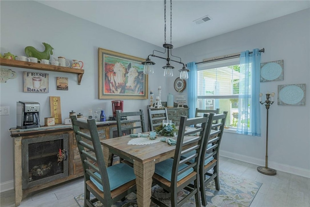 dining space with light wood-type flooring, visible vents, and baseboards