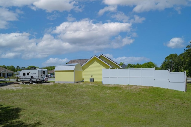 view of yard with a shed, central AC unit, an outdoor structure, and fence