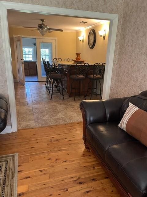 living room with ceiling fan, light wood-type flooring, and crown molding