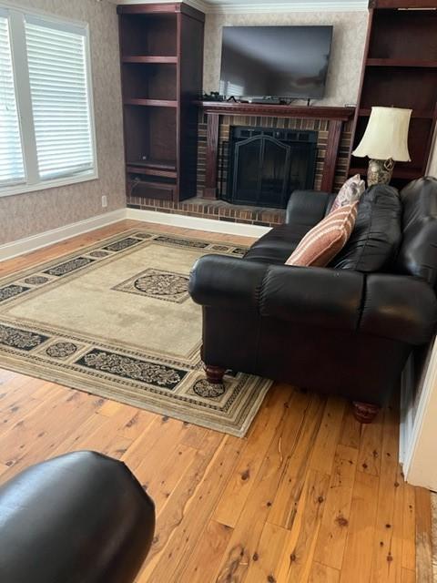 living room featuring a brick fireplace and hardwood / wood-style flooring