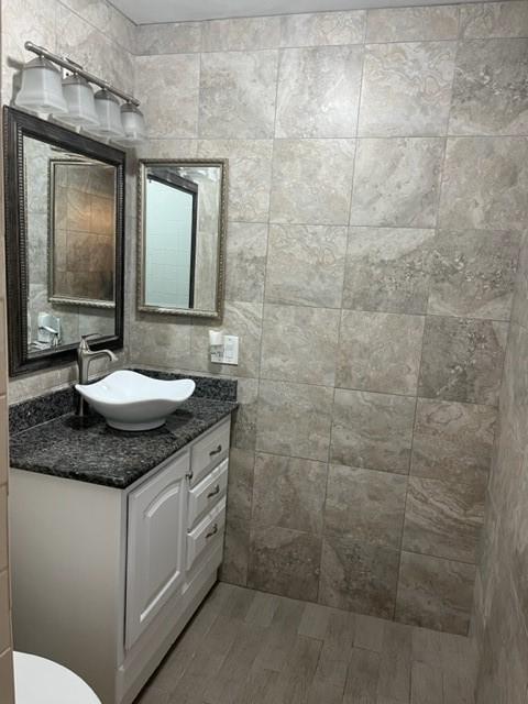 bathroom with hardwood / wood-style floors, vanity, and tile walls