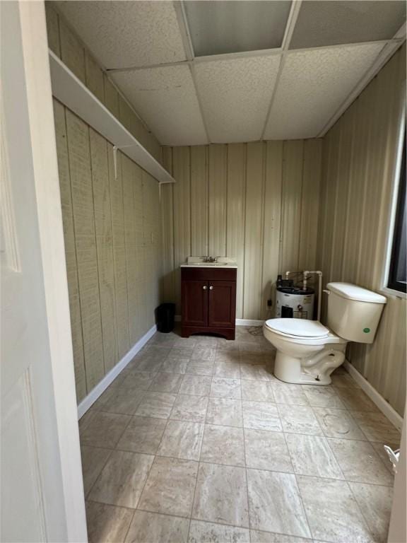 bathroom featuring wooden walls, a paneled ceiling, vanity, and toilet