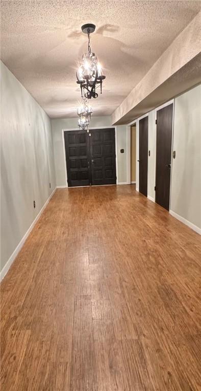 interior space featuring hardwood / wood-style flooring, a textured ceiling, and a chandelier