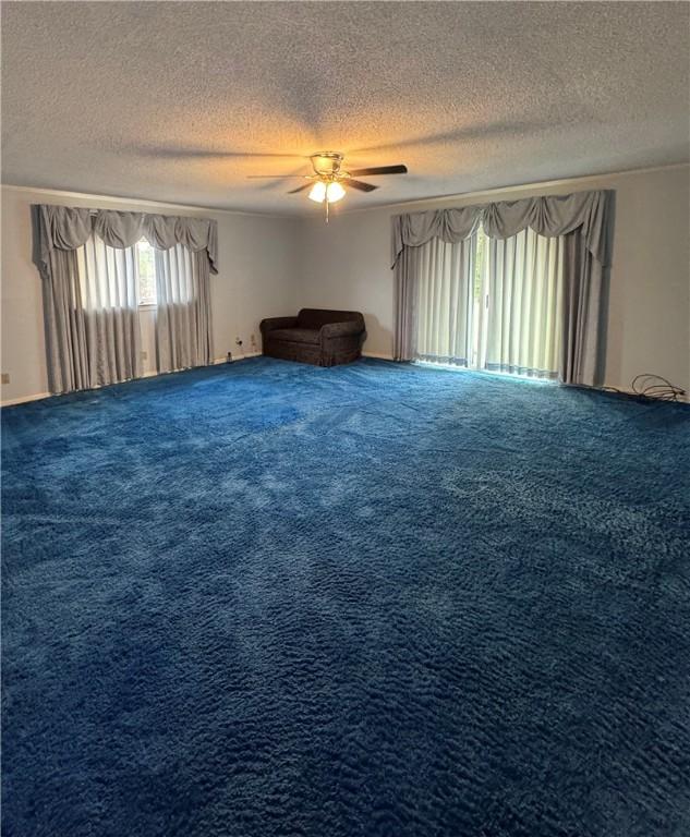 unfurnished room with ceiling fan, a textured ceiling, and carpet