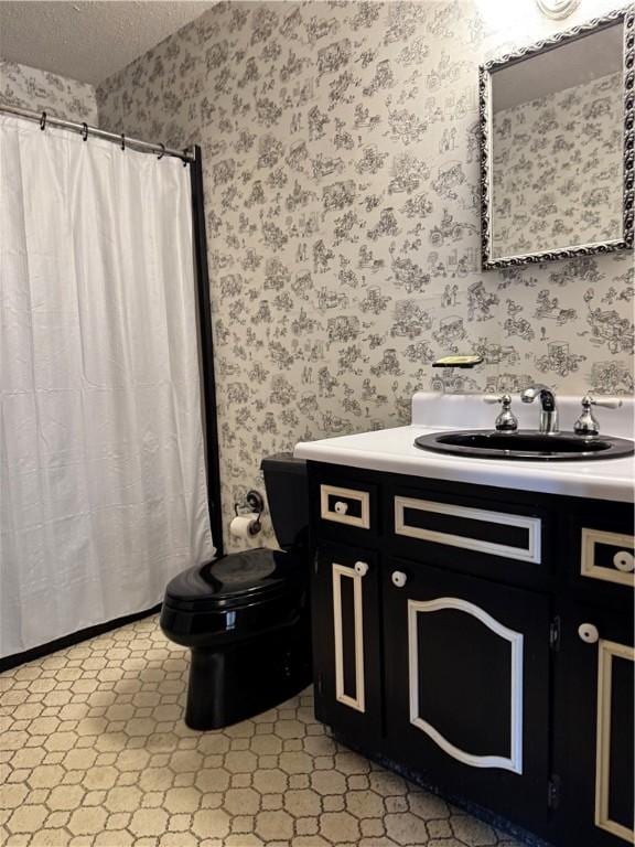 bathroom with vanity, toilet, and a textured ceiling