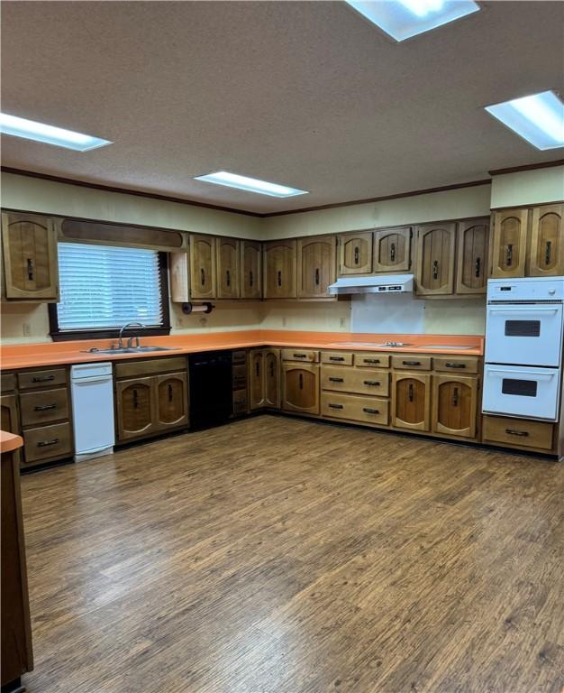 kitchen with sink, white double oven, dishwasher, dark hardwood / wood-style floors, and a textured ceiling