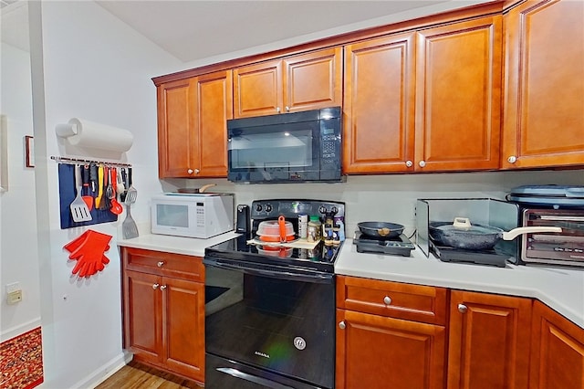 4718 Otter Creek Cir, Blackshear, GA 31516 - kitchen with black appliances, light countertops, brown cabinets, and light wood-style flooring