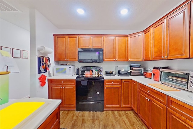 4718 Otter Creek Cir, Blackshear, GA 31516 - kitchen featuring black appliances, light wood-style flooring, light countertops, brown cabinetry, and recessed lighting
