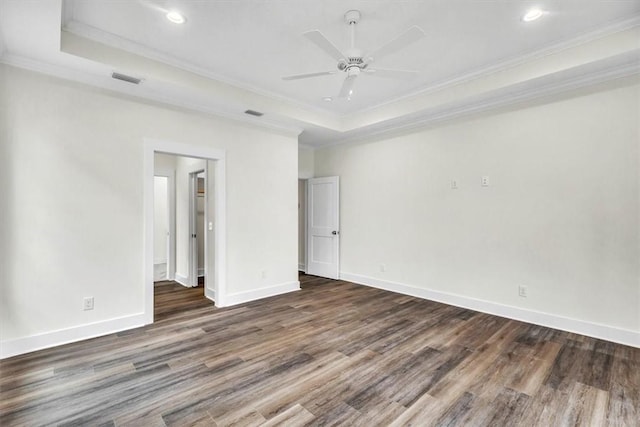 unfurnished bedroom with crown molding, dark wood-type flooring, ceiling fan, and a tray ceiling