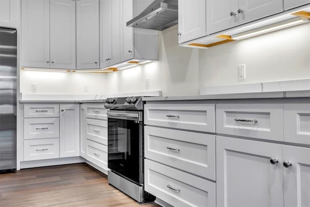 kitchen featuring appliances with stainless steel finishes, white cabinets, and wall chimney exhaust hood