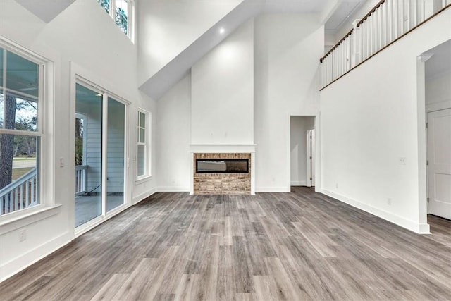 unfurnished living room with a wealth of natural light, wood-type flooring, and a multi sided fireplace