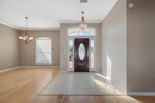 foyer with crown molding, an inviting chandelier, and light hardwood / wood-style flooring