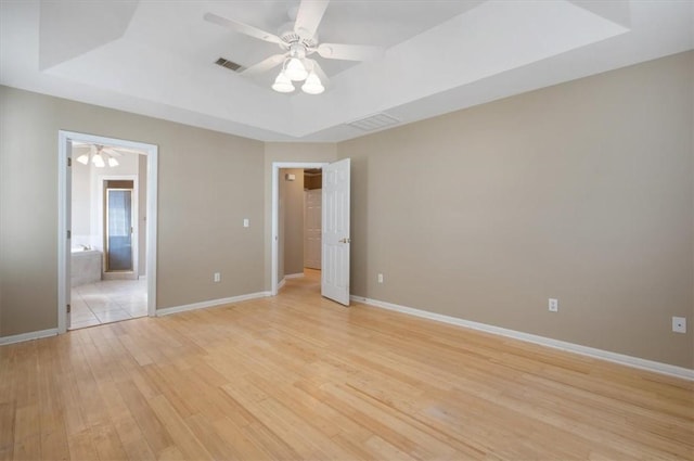 unfurnished bedroom featuring a raised ceiling, ceiling fan, and light hardwood / wood-style flooring