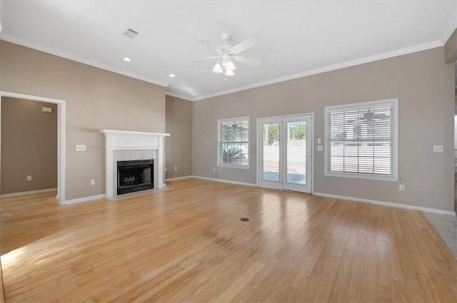 unfurnished living room featuring ceiling fan, light wood-type flooring, a tile fireplace, and crown molding