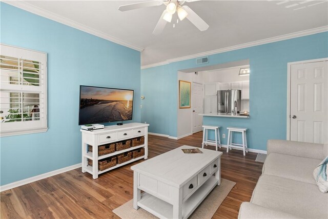 living room with ceiling fan, crown molding, and dark wood-type flooring