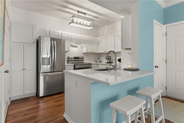 kitchen featuring a breakfast bar, sink, appliances with stainless steel finishes, white cabinetry, and kitchen peninsula