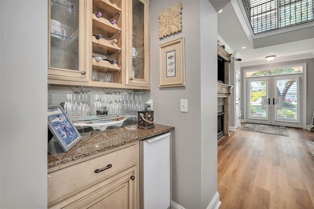 bar featuring stone countertops, french doors, light hardwood / wood-style flooring, and tasteful backsplash