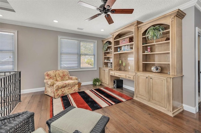 living area featuring ceiling fan, ornamental molding, a textured ceiling, and light wood-type flooring