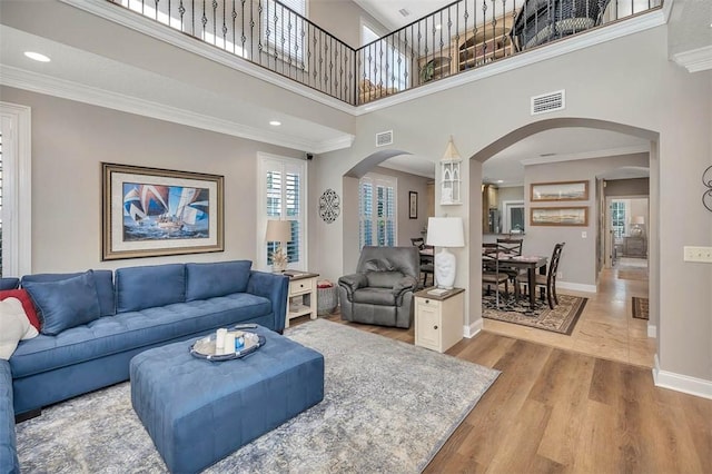 living room featuring hardwood / wood-style flooring, crown molding, and a high ceiling