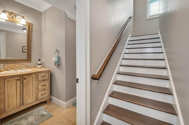 stairs with tile patterned floors, crown molding, and sink