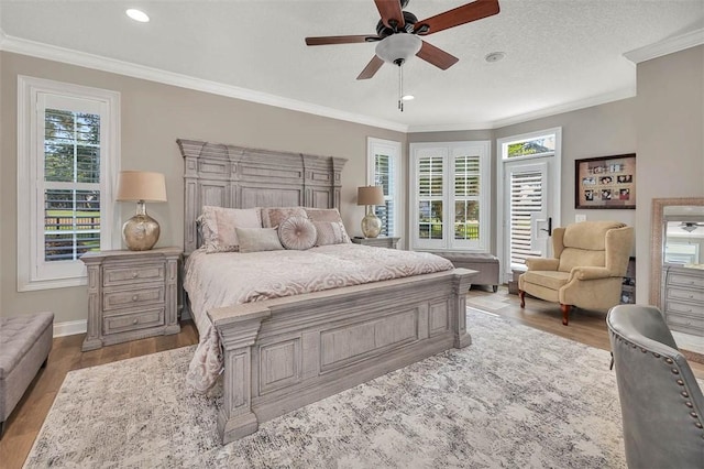 bedroom with ceiling fan, hardwood / wood-style floors, a textured ceiling, and ornamental molding