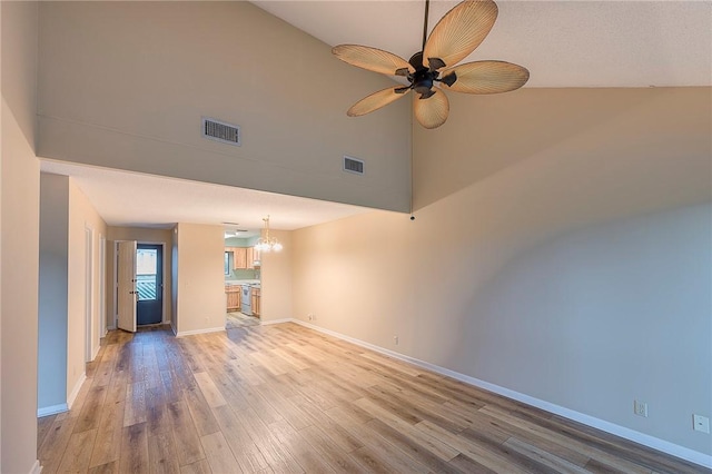 unfurnished living room featuring ceiling fan with notable chandelier, hardwood / wood-style flooring, and high vaulted ceiling