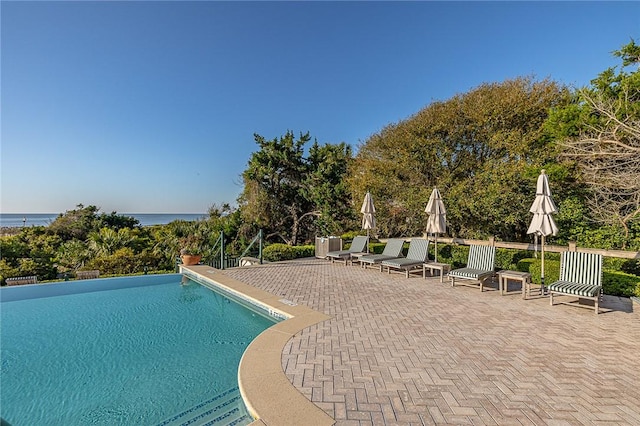 view of pool featuring a water view and a patio area