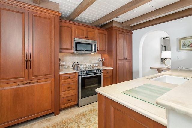 kitchen with appliances with stainless steel finishes, sink, backsplash, and beam ceiling