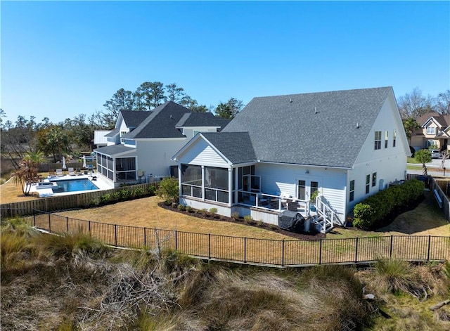 back of property with a sunroom, a fenced backyard, a fenced in pool, and a yard