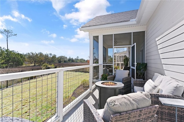 deck with an outdoor fire pit, a lawn, and a sunroom