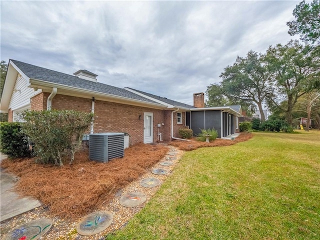 view of front of house with a sunroom, central AC unit, and a front yard