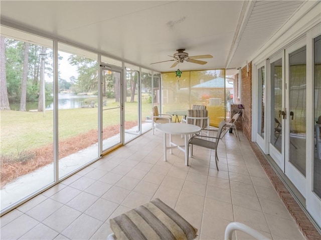 sunroom featuring a water view and ceiling fan