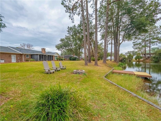 view of yard with a sunroom, a boat dock, and a water view