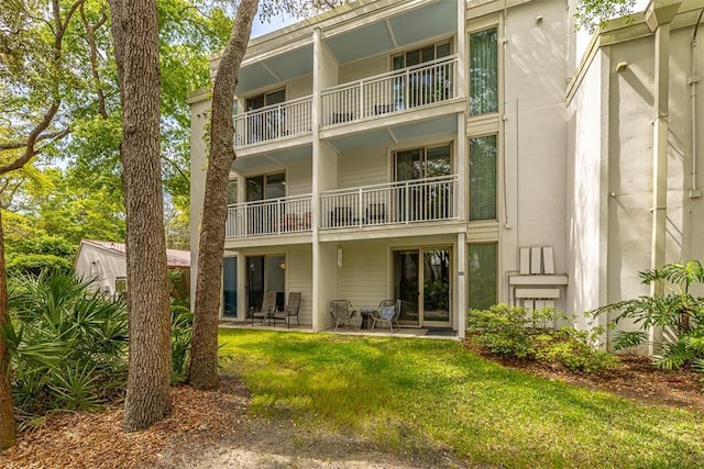 back of property featuring a lawn, a patio, stucco siding, and a balcony