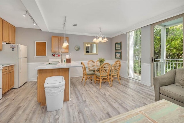 dining room featuring rail lighting, light wood finished floors, and a notable chandelier