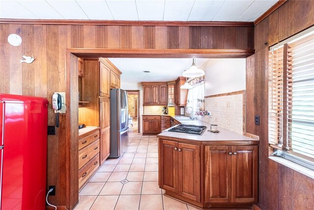 177 Pinewood St, Folkston, GA 31537 - kitchen featuring stainless steel appliances, brown cabinets, wood walls, light countertops, and light tile patterned flooring