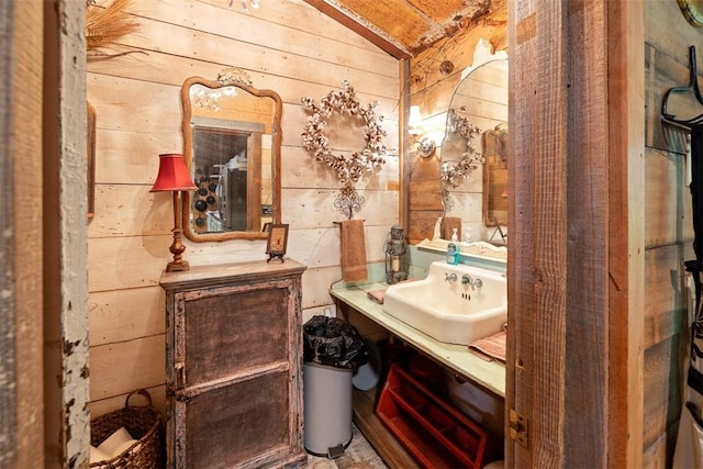 half bath featuring wood walls, vaulted ceiling, and vanity