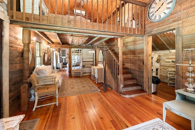 stairs featuring a high ceiling, wood finished floors, beam ceiling, and wooden walls