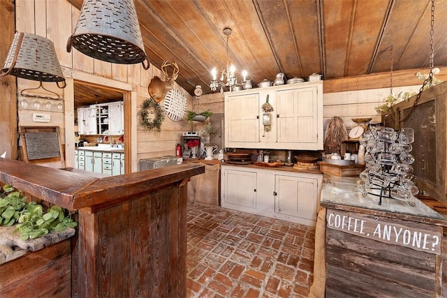 kitchen featuring brick floor, decorative light fixtures, an inviting chandelier, wood ceiling, and wooden walls