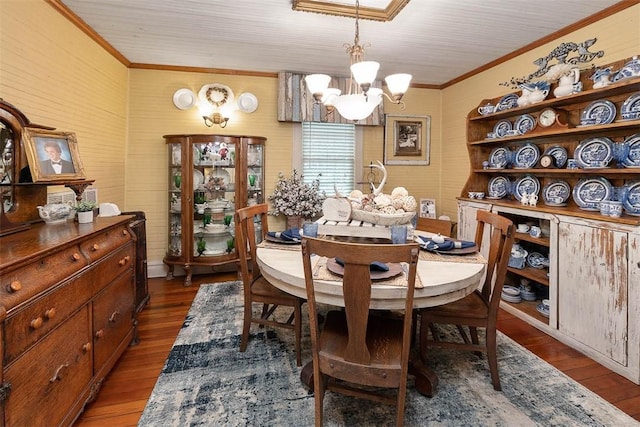 dining space featuring ornamental molding, dark wood-type flooring, and an inviting chandelier