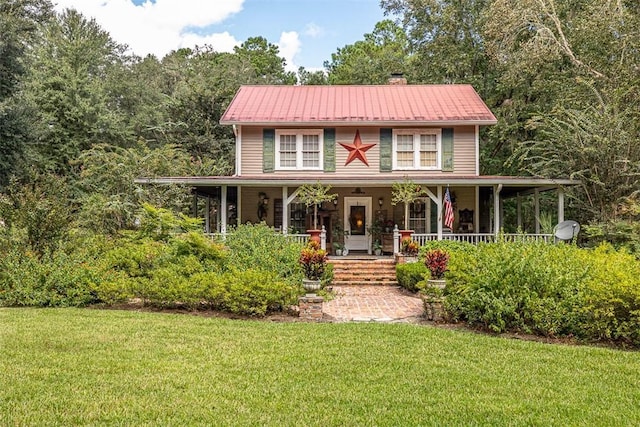 farmhouse-style home with metal roof, a porch, a chimney, and a front yard