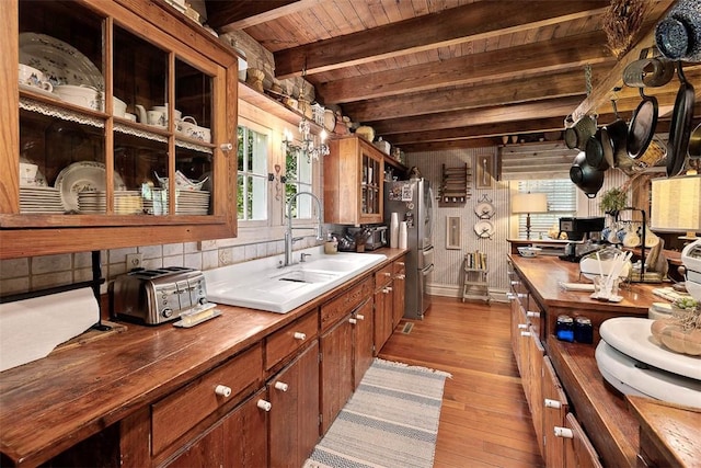 kitchen featuring wooden ceiling, light wood-style flooring, beamed ceiling, freestanding refrigerator, and a sink