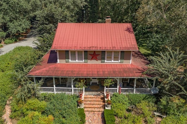 country-style home featuring covered porch, a chimney, and metal roof