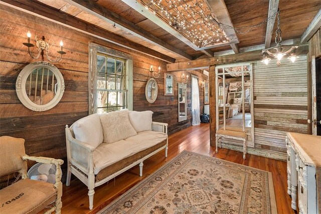 sitting room featuring wood walls, wood ceiling, dark wood-style flooring, and beamed ceiling