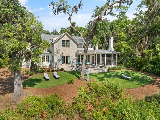 49 Hatton Ln, Saint Simons Island, GA 31522 - back of property with a sunroom, a yard, a standing seam roof, metal roof, and stucco siding