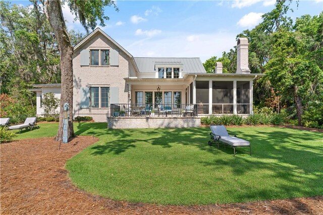 49 Hatton Ln, Saint Simons Island, GA 31522 - rear view of property featuring a chimney, a sunroom, a yard, and metal roof