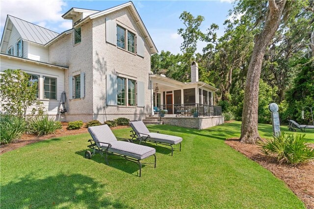 49 Hatton Ln, Saint Simons Island, GA 31522 - back of property with a sunroom, a lawn, brick siding, a standing seam roof, and metal roof
