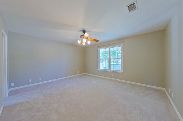 empty room with light colored carpet, baseboards, visible vents, and ceiling fan